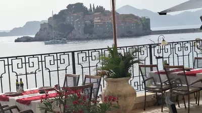 a table and chairs with a view of the water at Montesan Luxury Apartment Beach Front in Sveti Stefan