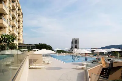 a swimming pool with chairs and umbrellas next to a building at Status-M Apartments 89 in Becici