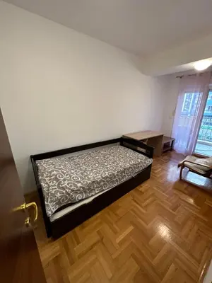 a bedroom with a bed and a wooden floor at Big apartment 2 in Podgorica