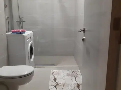 a white bathroom with a toilet and a sink at Apartman Podgorica in Podgorica
