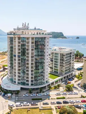 a large building with cars parked in a parking lot at Luxury 3 bedroom private apt in beachfront Hotel in Budva