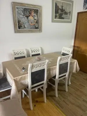 a dining room table with four chairs and a painting on the wall at Njegusi-Cetinje in Njeguši