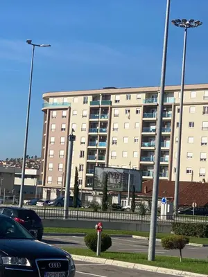 a large building with cars parked in a parking lot at Rent a apartment Podgorica in Podgorica