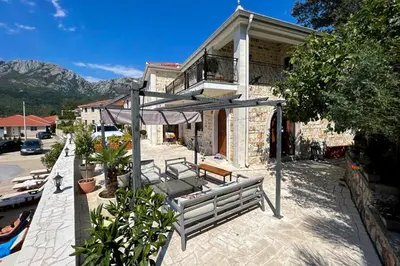 a house with a bench and an umbrella on a patio at Sutorman 2 Villa D&B in Zupci