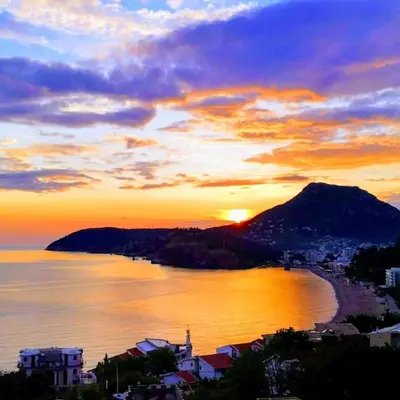 a sunset over a body of water with a mountain at Apartmanes Volaric M in Sutomore
