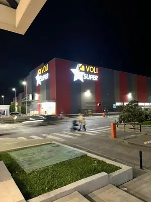 a person riding aooter in front of a building at night at Marija apartment City kvart in Podgorica