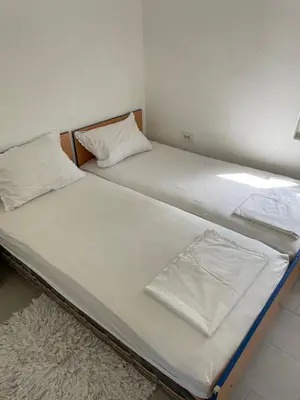 two beds in a room with white sheets and a rug at Grapefruit Home Apartment Ulcinj Montenegro in Donji Štoj