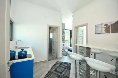 a kitchen with a sink and a counter with stools at Apartments Jadranski Biser in Čanj
