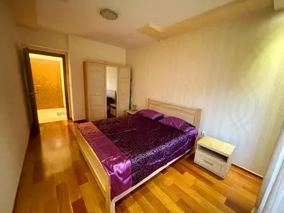 a bedroom with a purple bed and a wooden floor at City center apartment in Podgorica