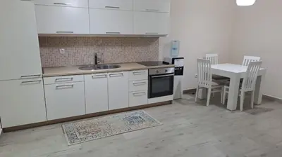 a kitchen with white cabinets and a table with chairs at Apartment D&A in Ulcinj