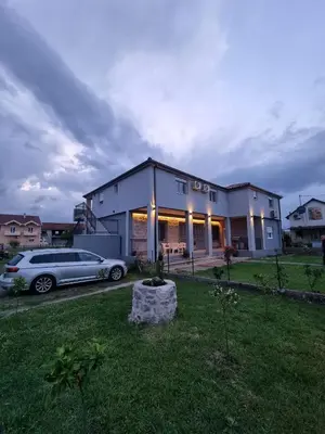 a house with a car parked in a yard at Bright & Cozy Apartment in quiet area near Airport in Golubovci