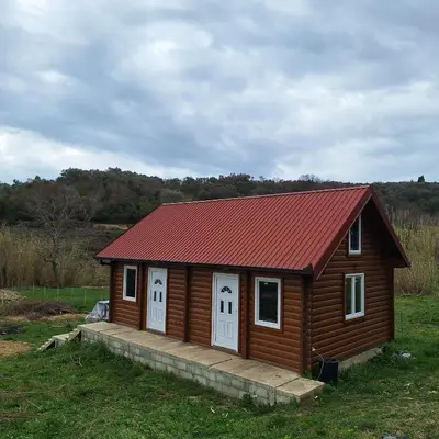 a small cabin with a red roof in a field at Cottage Kolomza in Ulcinj