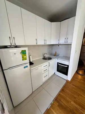a small kitchen with white cabinets and a refrigerator at Nema 2 in Kravlja