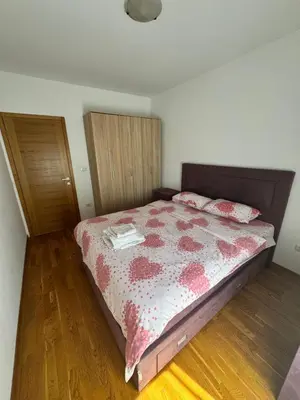a bedroom with a bed with a red and white comforter at City Apartment in Podgorica