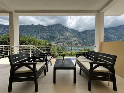 a balcony with three benches and a table with a view at Studio apartment with heated pool in Kotor