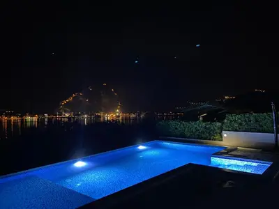 a swimming pool at night with a view of the water at Sea view apartment with heated pool in Kotor