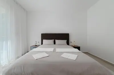 a white bedroom with a large bed with two white pillows at MM Apartments Gray in Budva