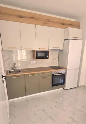 a kitchen with white cabinets and a sink and a refrigerator at Apartmani Banović 3 - Ulcinj, Velika plaža in Ulcinj