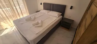 a bed with white sheets and white towels on it at Apartmani Banović 2 - Ulcinj, Velika plaža in Ulcinj