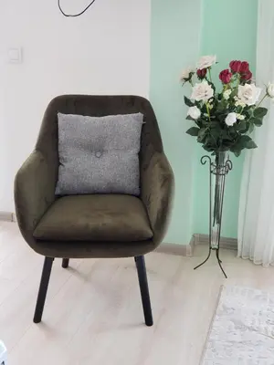 a brown chair with a pillow next to a vase of flowers at Уютная 1-комнатная квартира с видом на море! in Bar
