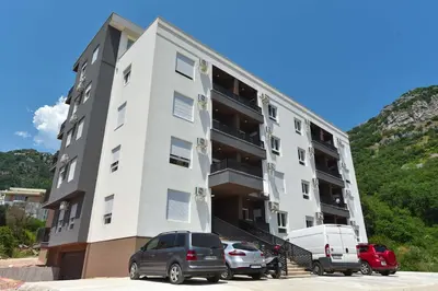 a white building with cars parked in front of it at Comfy one-bdr apartment Staša in Budva