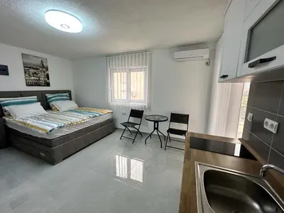 a bedroom with a bed and a table and a sink at Студия, 800 м до моря in Bar
