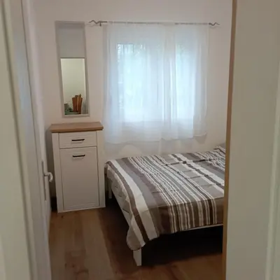 a bedroom with a bed and a dresser and a window at Nice summer apartment near sea in Budva