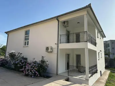 a white building with a balcony and some flowers at Apartmani Aki 1 in Sutomore