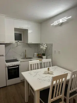 a kitchen with a white table and white cabinets at Apartman Budva Centar in Budva