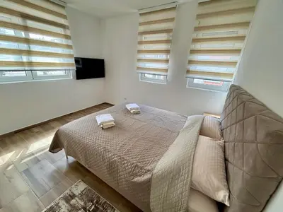 a bedroom with a bed and two windows at Apartman Živaljević 1 Tivat in Tivat