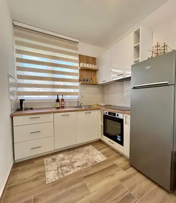a kitchen with white cabinets and a stainless steel refrigerator at Apartman Živaljević 1 Tivat in Tivat