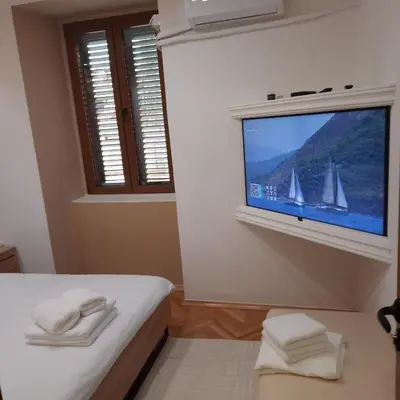 a bedroom with a bed with a tv on a wall at Apartman HOME Kotor in Kotor