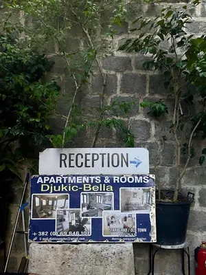 a sign in front of a brick wall with a sign at bella 11 in Kotor