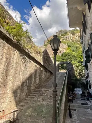 a street light next to a stone wall with stairs at bella 11 in Kotor