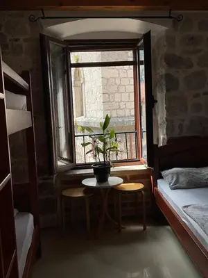 a room with a table and a window with a potted plant at bella 11 in Kotor
