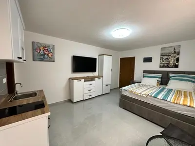 a bedroom with a bed and a flat screen tv at Студия в Добра Вода in Dobra Voda