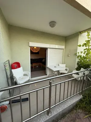 a balcony with white chairs and a table on it at two bedroom apartment with parking in Petrovac na Moru