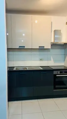a kitchen with black and white cabinets and a sink at Cozy city apartment Podgorica in Podgorica