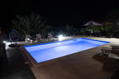 a swimming pool at night with chairs around it at Blue Escape in Danilovgrad