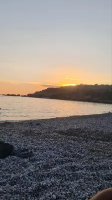a sunset on a rocky beach with the water at Martina 1 in Budva