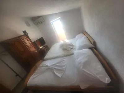 a bedroom with a bed with white sheets and a window at Asko Villa Apartment in Ulcinj