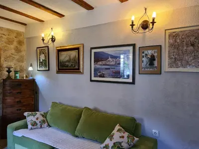 a living room with a green couch and pictures on the wall at Cheerful three bedroms house with free parking in Kotor