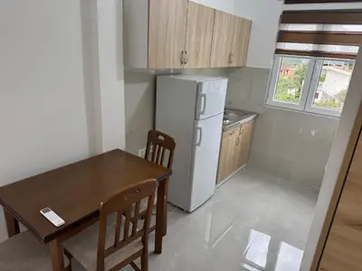 a small kitchen with a table and a refrigerator at Apartmani in Sutomore