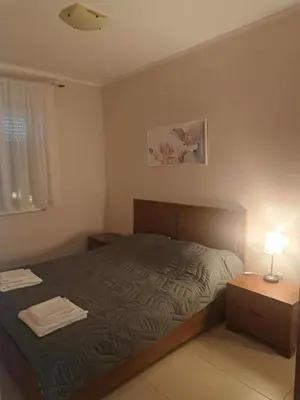 a bedroom with a bed and a table with a lamp at Apartman 3D in Podgorica
