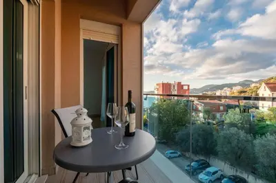 a table with two bottles and two wine glasses on a balcony at Apartment Pržno See View in Pržno