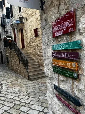 a group of signs on the side of a stone building at Athos Guesthouse in Kotor