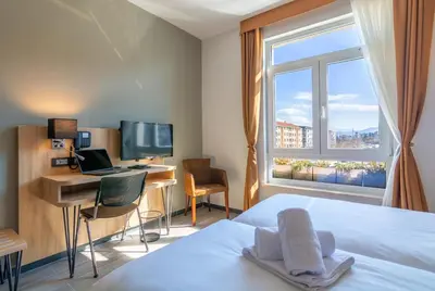 a bedroom with a bed and a desk with a computer at Hotel Resurs in Podgorica
