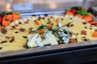 a tray of food with cheese and vegetables on it at Villa Dvor Kornic in Budva