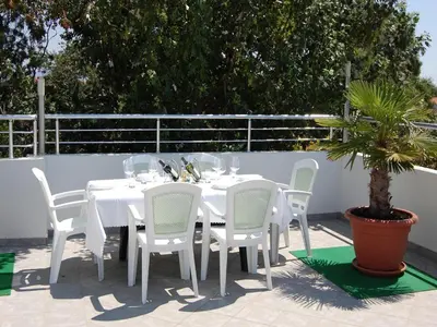 a white table with white chairs and a potted plant at Villa Elkom, Appartment 7 in Donji Štoj