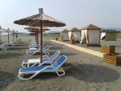 a row of lounge chairs and an umbrella on a beach at Villa Elkom, App 6 in Ulcinj